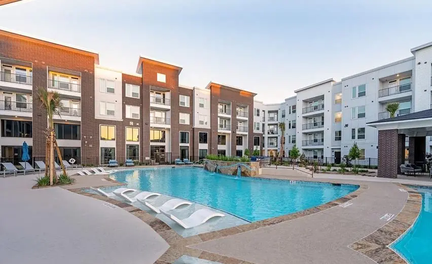 Apartment community pool with shaded seating and a clubhouse deck
