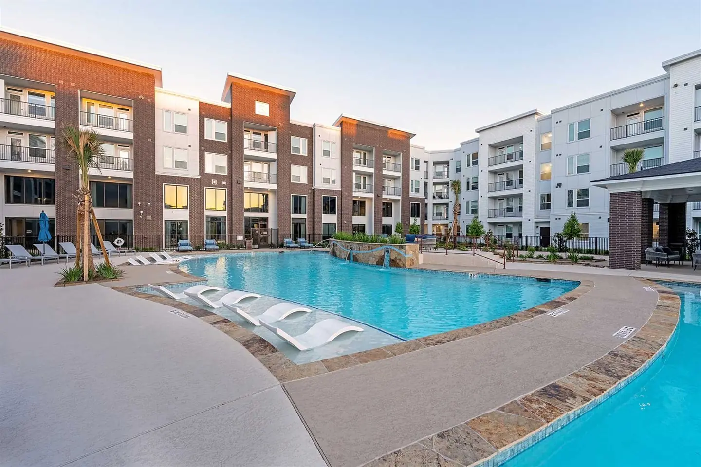 Apartment community pool with lounge chairs and a sun shelf