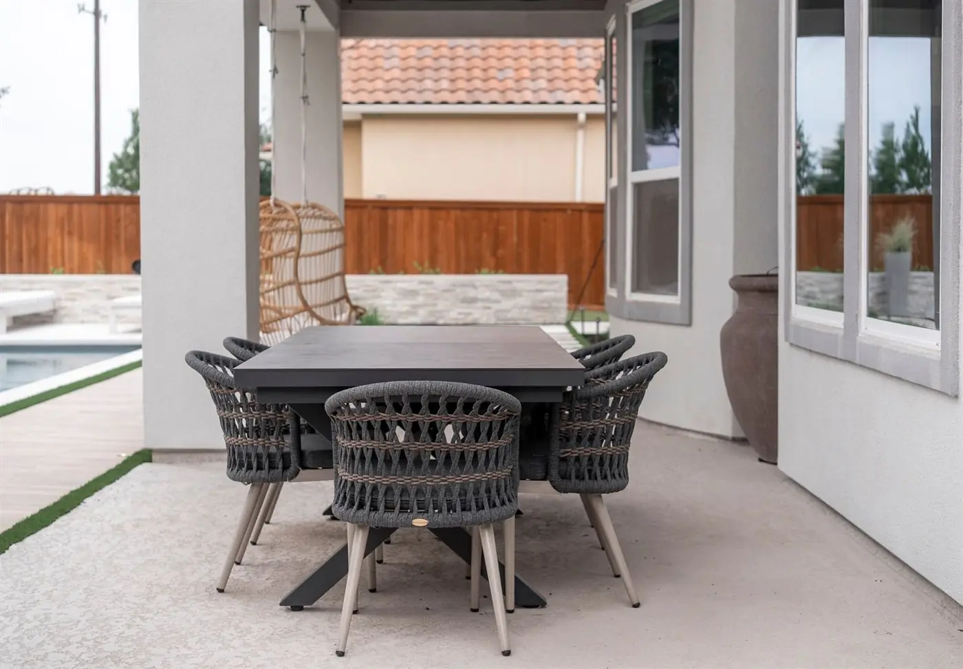 Covered patio with a dining table and woven chairs beside the house