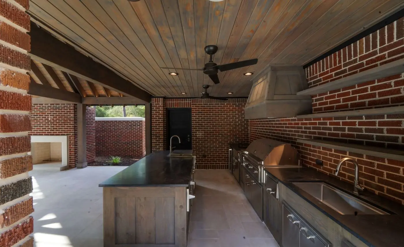 Covered outdoor kitchen with grill, bar seating and warm lighting