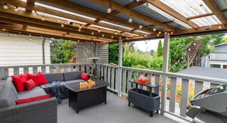 Covered deck with a gas fire table, string lights and outdoor sofas