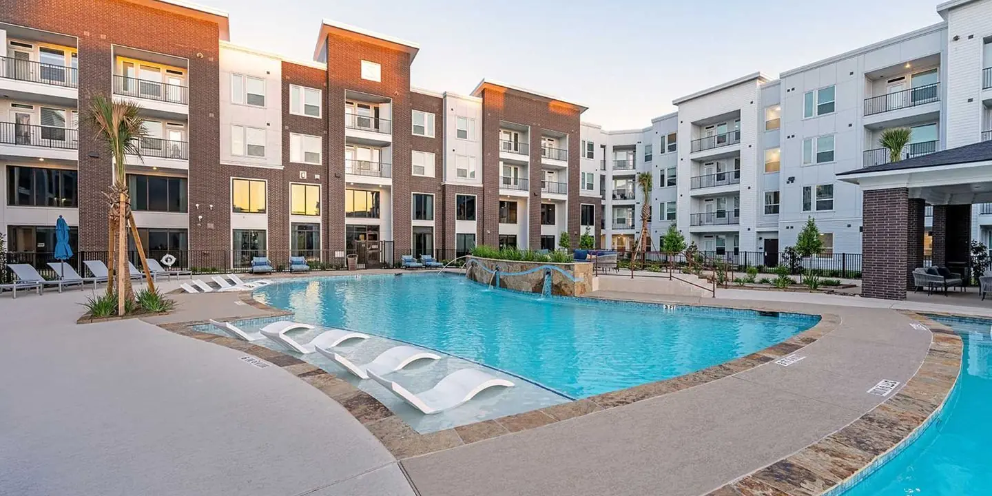 Apartment community pool with lounge chairs and a sun shelf