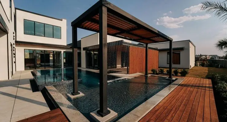 Modern dark-framed pergola with a louvered roof over a pool and wood deck