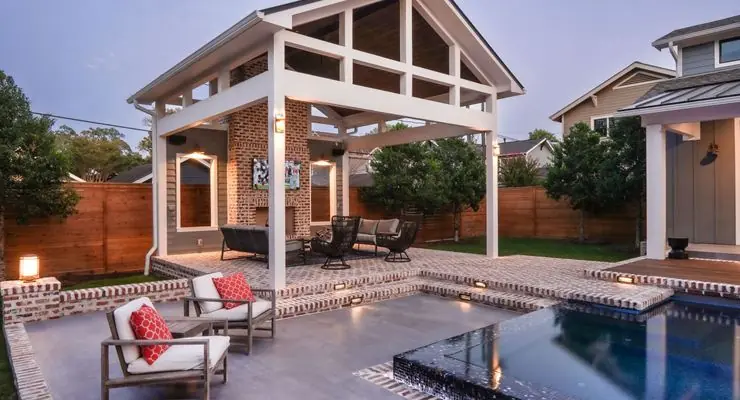 Gabled pergola with brick columns beside a patio and pool