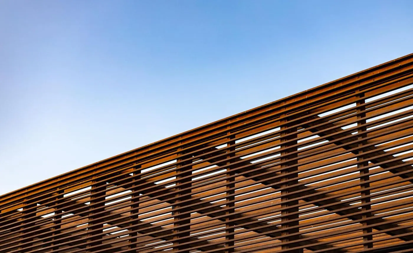 Slatted wooden pergola roof against a clear blue sky